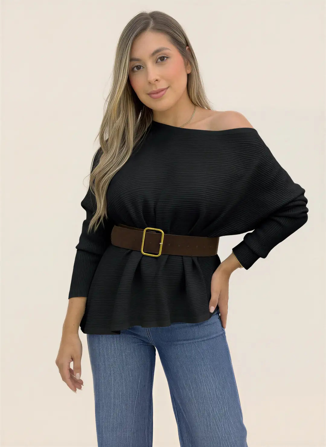 Mujer luciendo blusa tejida negra de manga larga, escote amplio y textura acanalada, combinada con jeans.