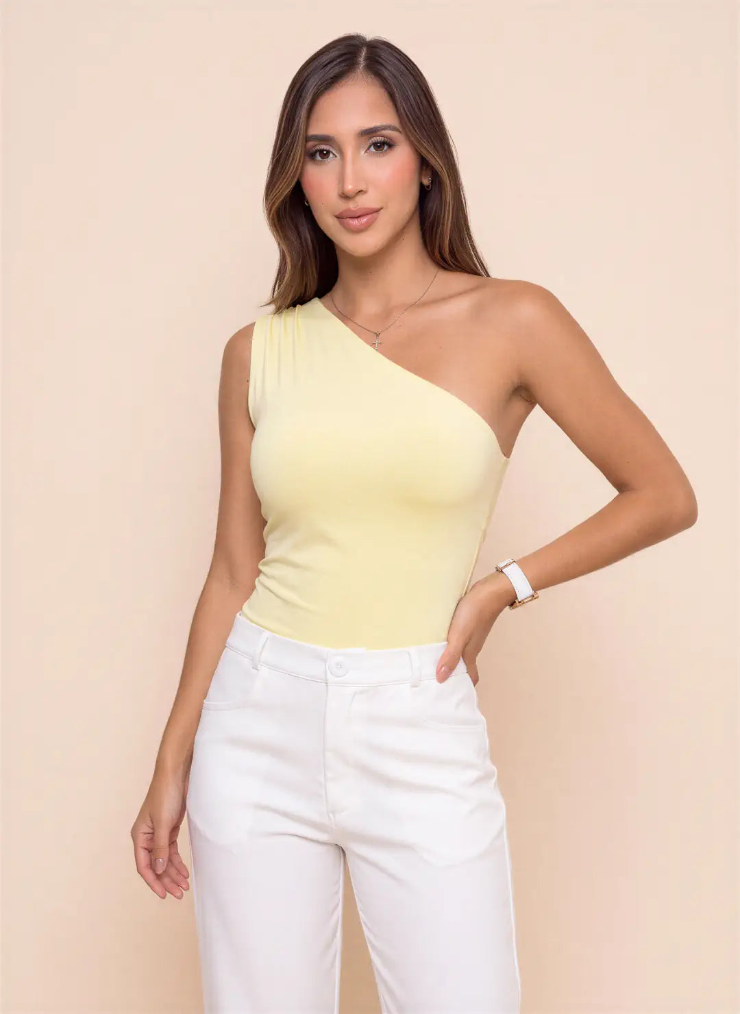 Modelo luciendo body amarillo pastel de un solo hombro con escote asimétrico y diseño ajustado, combinado con pantalón blanco de mujer.