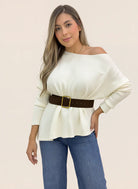 Mujer luciendo blusa tejida marfil de manga larga, escote amplio y textura acanalada, combinada con jeans.