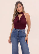 Modelo luciendo blusa vinotinto halter con escote drapeado tipo cascada, textura acanalada y hombros descubiertos de Coral.