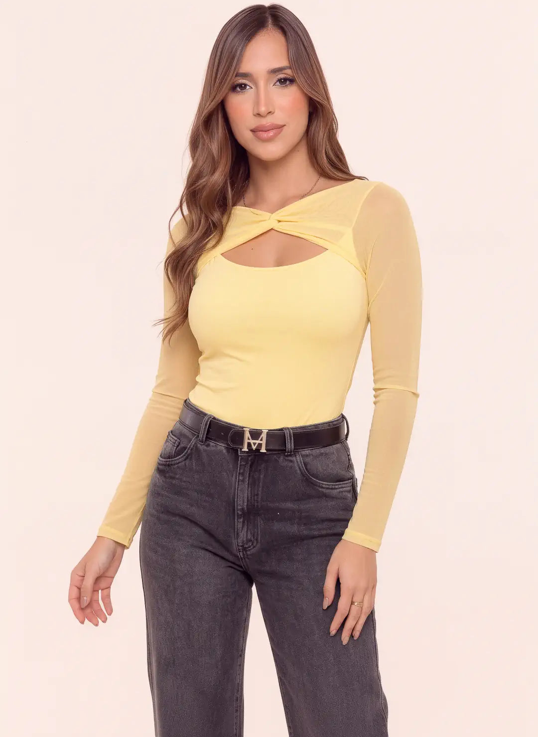 Body amarillo pastel para mujer con escote cruzado, abertura frontal y mangas largas en mesh semitransparente, combinado con jean gris.