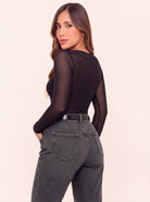 Vista posterior de body negro para mujer con mangas largas en mesh transparente y espalda semitransparente, combinado con jean gris.